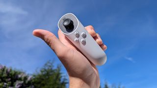 Xbox Adaptive Joystick held in hand, up to a blue cloudy sky