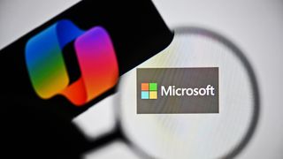 In this photo illustration the logo of Microsoft is being displayed on a laptop screen and the logo of Copilot is being displayed on a smart phone.